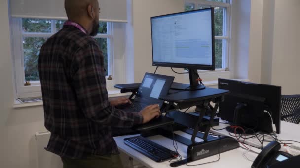 オフィスの人間工学に基づいたスタンディングデスクでラップトップを使用して大人の男性 ロックオフ — ストック動画