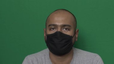 Yetişkin erkek, pamuk maskeli, sallanan kafa kameraya bakıyor. Krom Anahtar, Kilitli