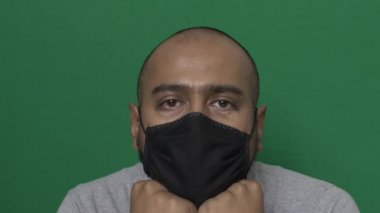 Çenesinde elleri dinlenen siyah maskeli yetişkin bir erkek var. Kilitli, Yeşil Ekran