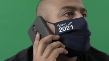 Yetişkin erkek, 2021 'de cep telefonuyla konuşan maske takıyor. Yeşil Ekran, Kilitli
