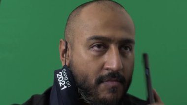 Yetişkin bir erkek 2021 'de cep telefonuna cevap vermek için maske takıyor. Yeşil Ekran, Kilitli