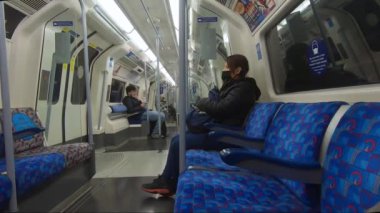Londra yeraltı trenindeki yolcular yüz maskeleri ve sosyal mesafeler takıyorlar. 