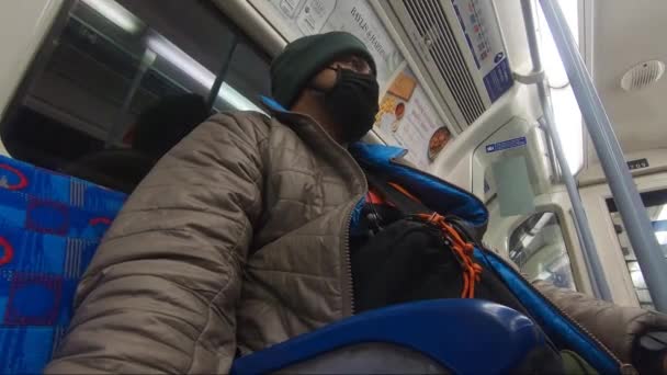 ロンドン地下鉄で顔マスクと帽子を身に着けている大人男性 低角度 — ストック動画