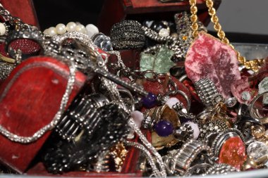 Yüzüklerle, kolyelerle, farklı boyutlarda ve renkte bileziklerle farklı sandıklarda çeşitli mücevherler.