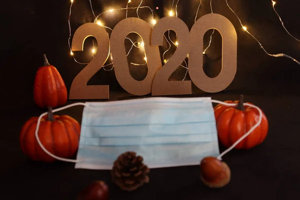 Blue mask against the coronavirus on halloween with pumpkins and the numbers of the year 2020