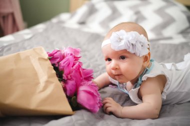 Yatakta yatıyordu ve ping buket pion çiçek ile oynamaya yeni doğan bebek