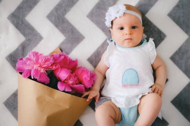 Yatakta yatıyordu ve ping buket pion çiçek ile oynamaya yeni doğan bebek