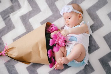 Yatakta yatıyordu ve ping buket pion çiçek ile oynamaya yeni doğan bebek