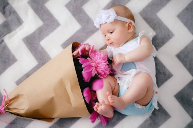 Yatakta yatıyordu ve ping buket pion çiçek ile oynarken mutlu yeni doğan bebek