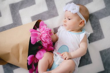 Yatakta yatıyordu ve ping buket pion çiçek ile oynamaya yeni doğan bebek