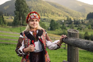 Beautiful caucasian woman wearing ethnic and traditional of the Carpathian mountain Ukrainian clothes. Village background in the autumn. clipart