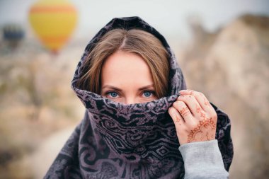 Tatlı kadın portre eşarp, güzel gözleri ve mehendi kına dövme yandan Cappadocia peyzaj ve sıcak hava balon arka plan üzerinde de günbatımında kapsadığı yüz
