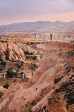 Küçük turistik insanlar büyük güzel dağ manzara ve günbatımı gökyüzü gül Vadisi Türkiye'de seyahat manzarasının keyfini Kapadokya'da kaldırdı elleriyle