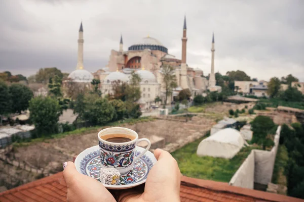 Cup of turkey coffee in tourist woman hands on Hagia Sophia famous islamic Landmark mosque, Travel to Istanbul, Turkey background