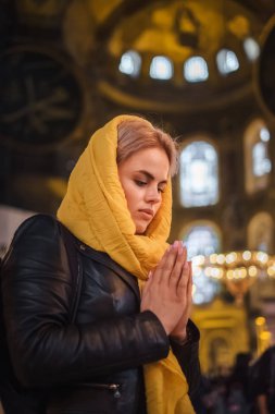 Christian Religion Concept. Young woman praying and feel God blessing in her heart in Hagia Sophia, Istanbul, Turkey clipart