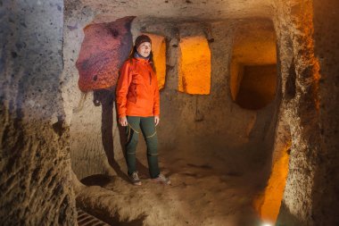 Güzel turist kadın keşfetmek antik Kaymaklı yeraltı cave City uzun dar tünel. Türkiye'ye seyahat