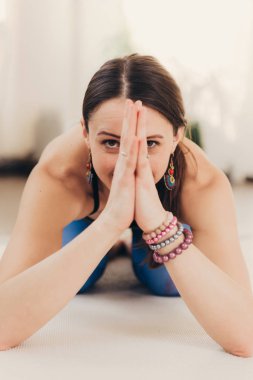 Bir güneşli sabah stüdyoda güzel genç kadın meditasyon ve yapıyor namaste el hareketi portresi.