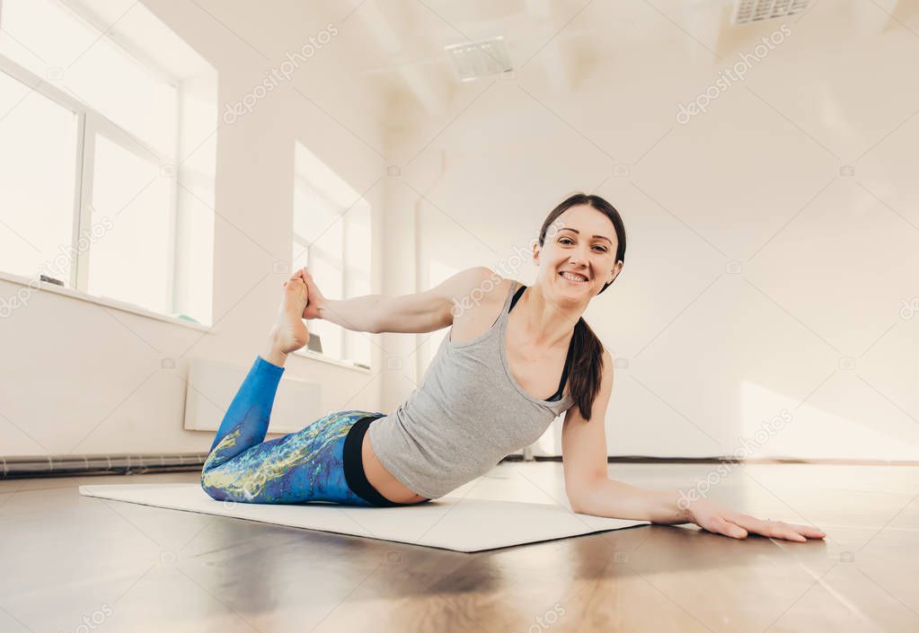 Happy smiling caucasian yoga instructor practicing yoga on in white studio at the morning