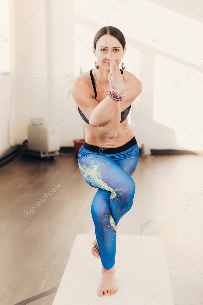 Happy smiling caucasian yoga instructor practicing yoga on in white studio at the morning