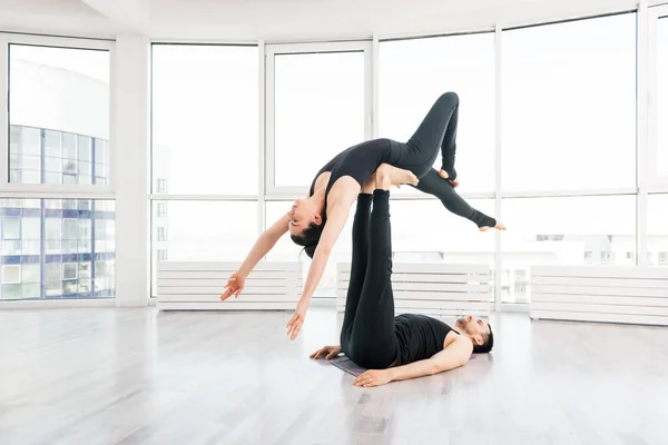 Casal jovem fazendo acro ioga em par no estúdio — Fotografia de Stock