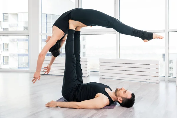 Casal jovem fazendo acro ioga em par no estúdio — Fotografia de Stock