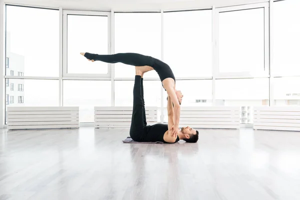 Положительная женщина практикует акро йогу с мужчиной партнером в студии — стоковое фото