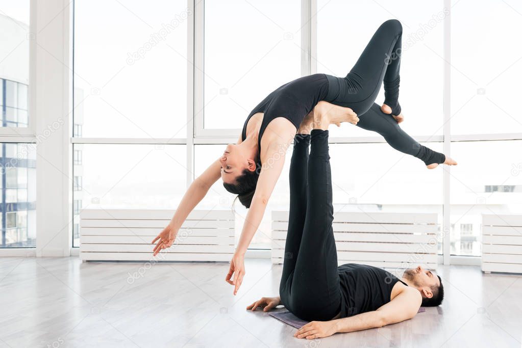 Young couple doing acro yoga in pair at studio