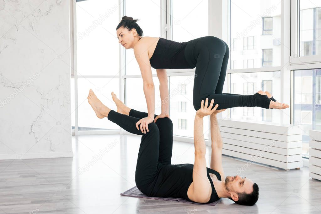 Positive woman practice acro yoga with man partner at studio