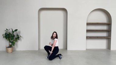 Parlak, modern bir stüdyoda zarif bir yüksek topuklu dans gösterisi yapan kadın..