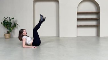 Parlak, modern bir stüdyoda zarif bir yüksek topuklu dans gösterisi yapan kadın..