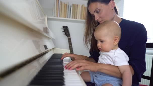 Una Linda Mami Tocando Piano Blanco Con Bebé Enseñándole Tocar — Vídeo de stock
