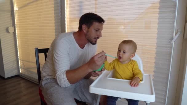 Un padre che da 'da mangiare al bambino a casa. Al bambino non piace il cibo e lo sputa fuori.. — Video Stock