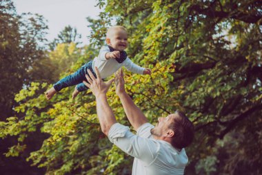 Çekici bir baba nazikçe havaya bebek fırlatıyor..