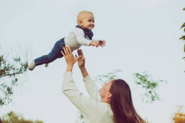 Çekici bir anne nazikçe havaya bebek fırlatıyor..