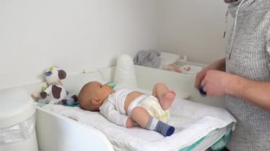 Sevimli bebeğinin altını değiştiren nazik bir baba.