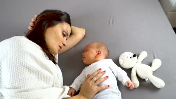 Madre reconfortante cólicos de su hermoso bebé en una cama 4K — Vídeos de Stock