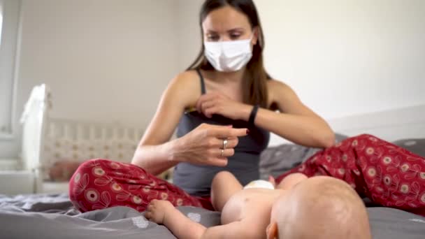 COVID19 mother with mask and baby boy measuring tempereature with thermomether — Stock Video