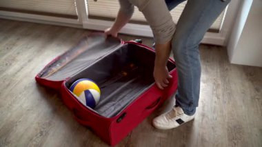 Bir adam sadece plaj voleybolunu valize koyar.