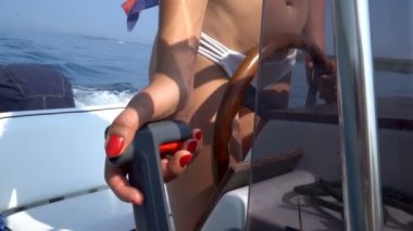 Beyaz bikinili ve kırmızı tırnaklı bir kadın denizde lastik bir tekne kullanıyor.