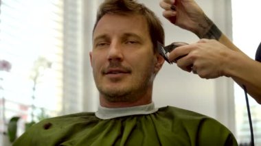 Kuaförde saç kesme makinesi 4K ile saçını kestiren bir adam.