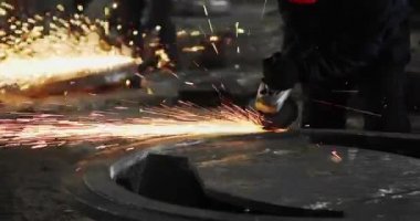 Metal açı öğütücüsünde kıvılcımlar çıkıyor. Öğütücünün dönen diskinin etrafında bir sürü parıldayan kıvılcım uçuşuyor..