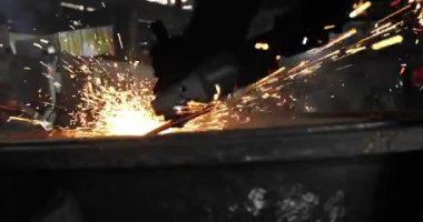 Metal açı öğütücüsünde kıvılcımlar çıkıyor. Öğütücünün dönen diskinin etrafında bir sürü parıldayan kıvılcım uçuşuyor..