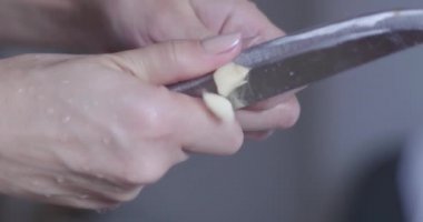 Kesme tahtasındaki soğan. Bıçaklı bir kadının elleri kesme tahtasındaki soğanı dilimliyor. Masadaki soğan..