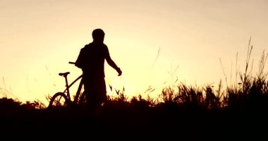Gün batımında bir bisikletçi figürü
