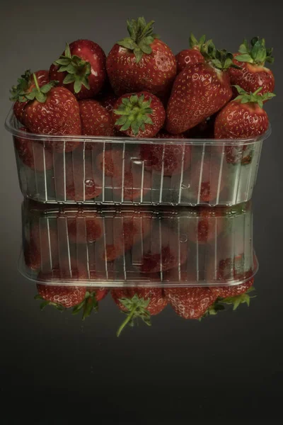 Frische Erdbeeren Einer Durchsichtigen Plastikbox Auf Spiegelschwarzem Hintergrund Erdbeeren Sind — Stockfoto