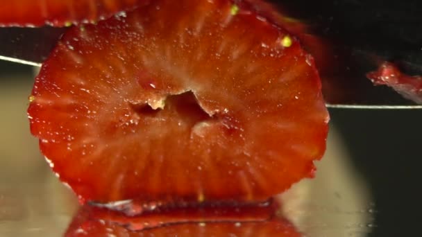 木の板にイチゴを切る女性の手 イチゴのスライス 大きなナイフはイチゴを2つのスライスに切りました マクロ撮影 — ストック動画