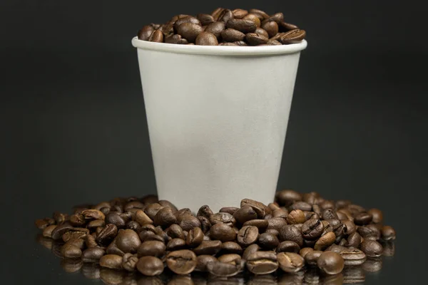 濃いテーブルの上にコーヒー豆とコーヒー豆の紙コップ — ストック写真