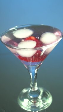 Profesyonel bir barmenin makro 'su, barda veya disko kulübünde müşterilere alkollü kokteyl hazırlarken profesyonel kristal buz küplerini bardağa koyuyor. Akıllı telefonlar ve tabletler için dikey video