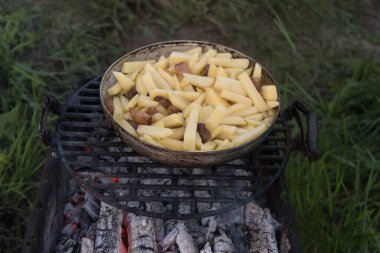 Kömürün üstündeki tavada çiğ patates. Açık hava barbeküsü. Yemek hazırlama, üst manzara