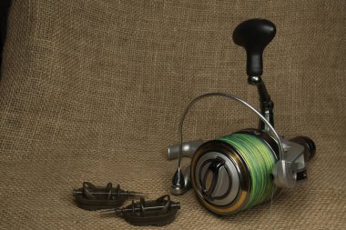 Balıkçılık, arka planda çuval beziyle sazan balığı makarası. Çuval bezi arka plan. Çuval beziyle sazan balığı makarası. Çuval bezi arka planı.